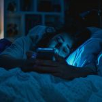 Kako telefoni utiču na mozak i san – osoba gleda u telefon u mraku